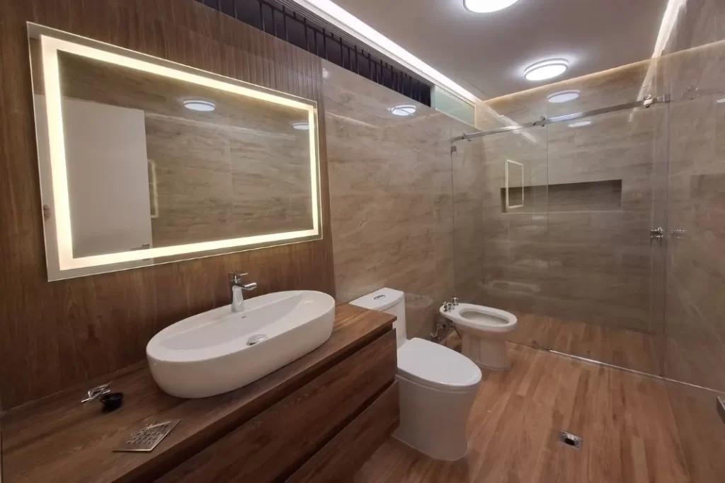 Baño principal remodelado en Chacao Caracas, Venezuela, con espejo iluminado, ducha de cristal y acabados de primera.